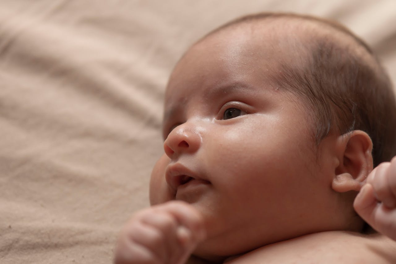 Close-up profile view of an adorable newborn baby lying on a soft surface.
